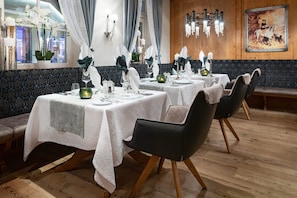 A restaurant with tables set for dining, wooden flooring, and a chandelier.