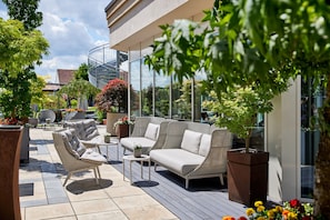 A patio with wicker furniture, a glass balustrade, and potted plants.