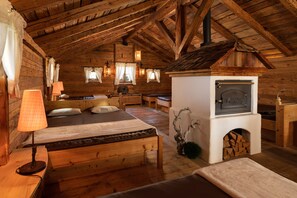A log cabin interior with a bed, a fireplace, and a dining area.