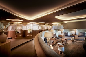 A modern interior with a curved seating area, wooden flooring, and multiple lamps.