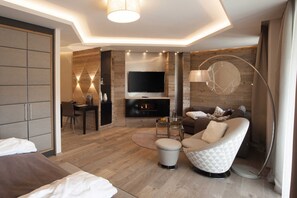 A modern living room with a flat-screen TV, a fireplace, a sofa, a coffee table, and a dining area.