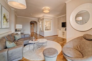 Un salon moderne comprenant un canapé, un pouf, une table basse et un miroir rond.