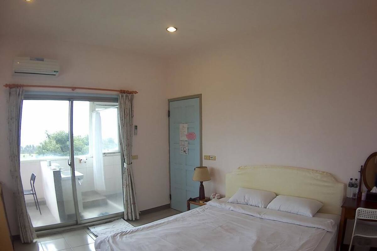 Una habitación de hotel con una cama, un escritorio, una silla, una lámpara y un ventanal corredero que da a un espacio al aire libre.