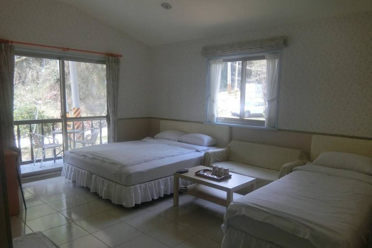 Una habitación con dos camas, una mesita y una ventana.