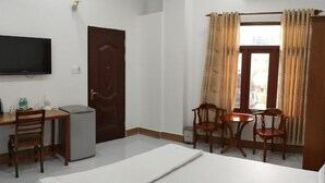 A hotel room with a bed, a desk with a chair, a television, and a window with curtains. - Ngoc Han Hotel (Thoi Son)