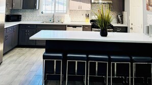 Een moderne keuken met donkere kastjes, een groot eiland met barstoelen en een dakraam.