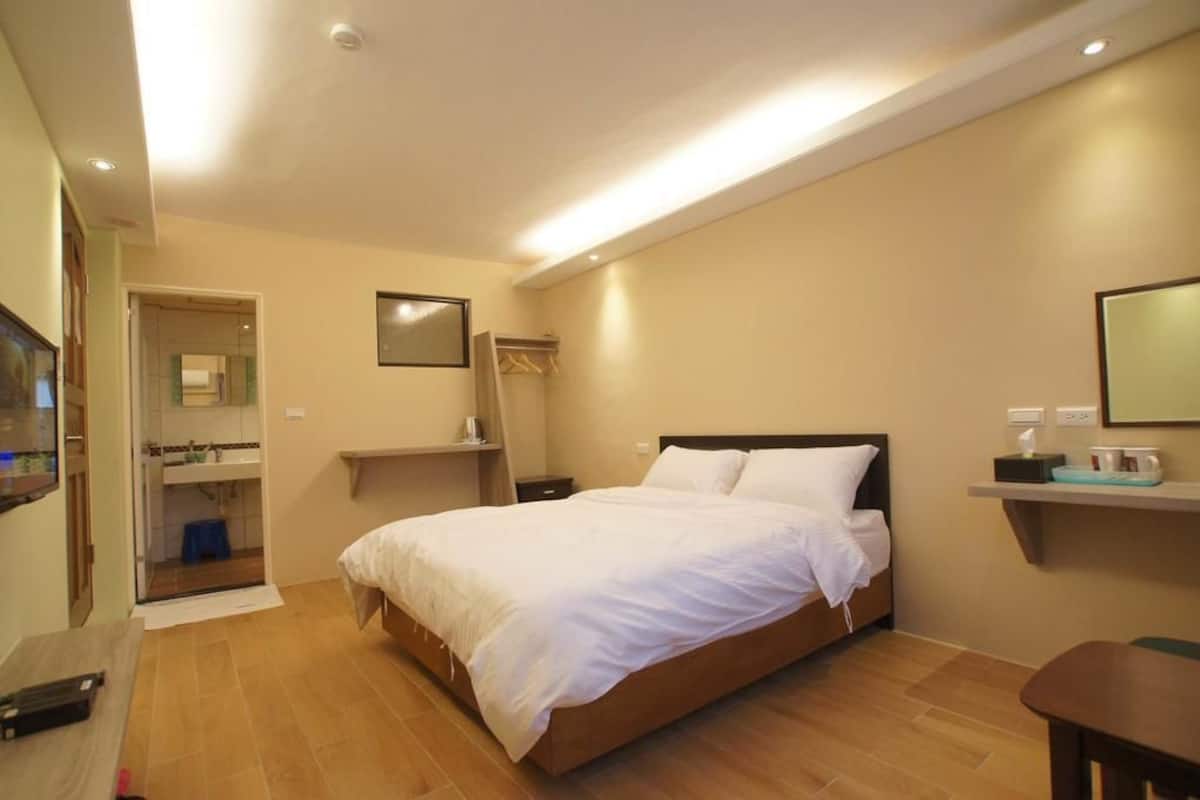 Ein Schlafzimmer mit Bett, Nachttischen, einem Spiegel und einer Ablage mit Pflegeprodukten.