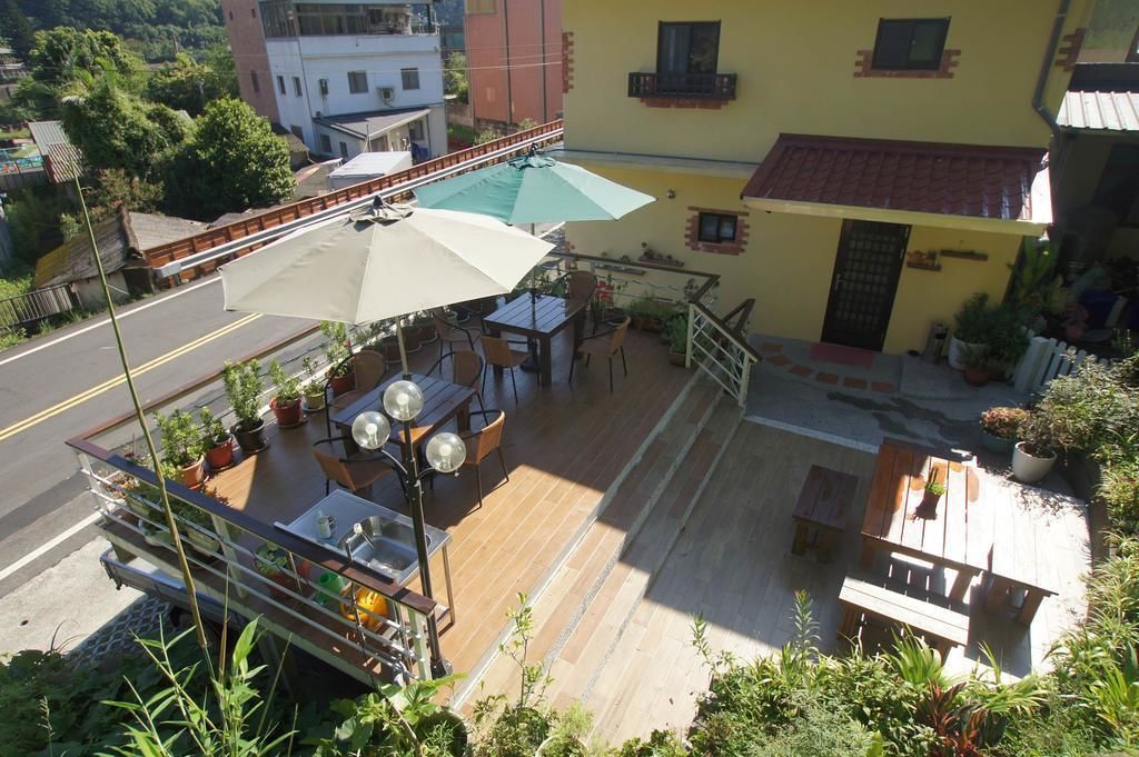 A rooftop patio with outdoor seating, a table with a green umbrella, and potted plants.