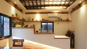 Ein Essbereich mit Backsteinwand, Holzbalkendecke und einem Fenster mit Rollläden.