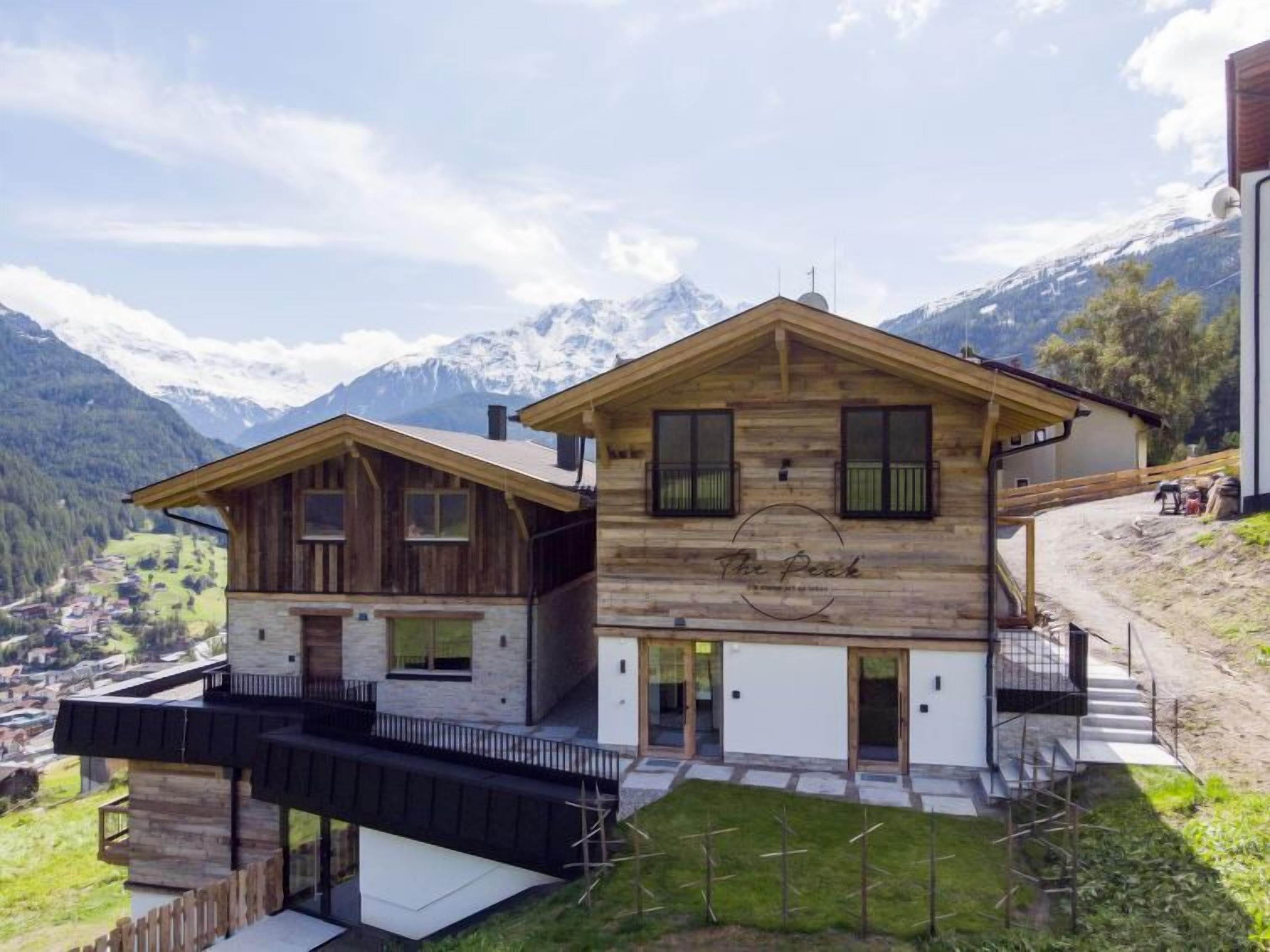 Eine Holzhütte mit Balkon, einer Steinfassade und Blick auf Berge.