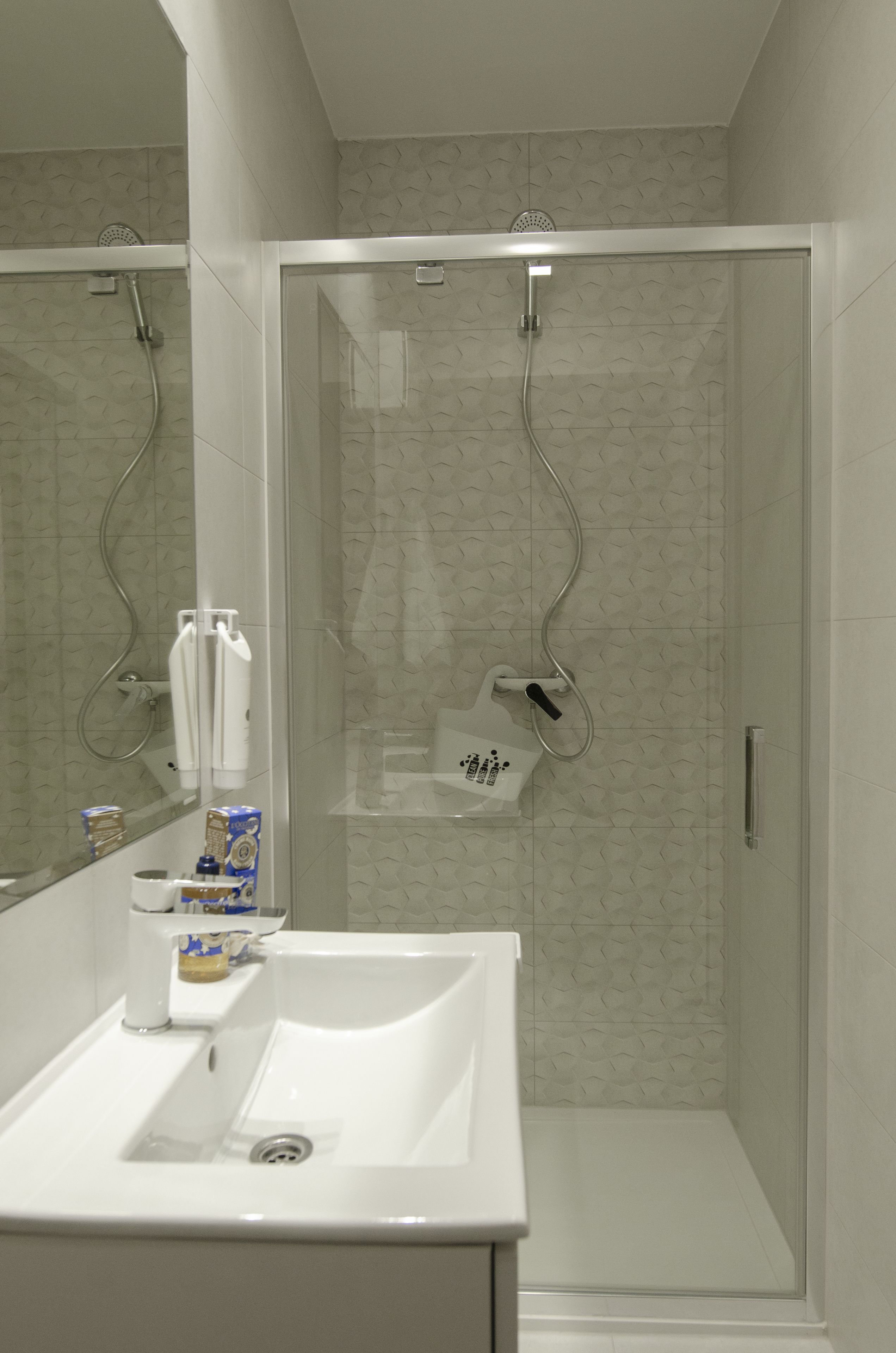 A modern bathroom with a glass-enclosed shower, a white sink, and a mirror.