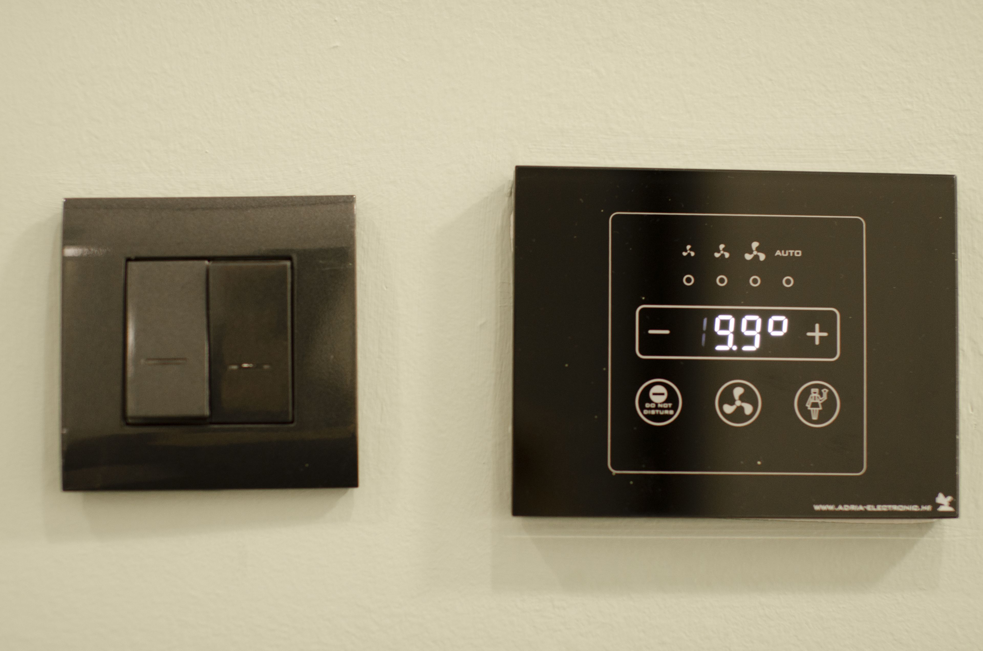 Un termostato con pantalla digital e interruptor fijado a la pared.