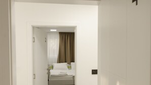 Ein Hotelzimmer mit einem Bett, einem kleinen Tisch und einem Stuhl. Eine Tür mit der Nummer 4 ist zu sehen.
