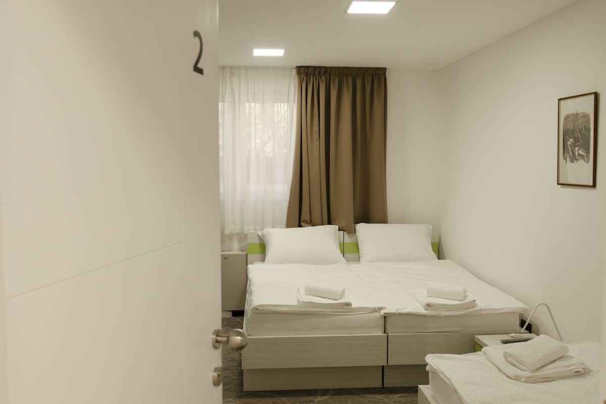 A hotel room with a double bed, a bedside table, a nightstand, a lamp, and a framed picture on the wall.