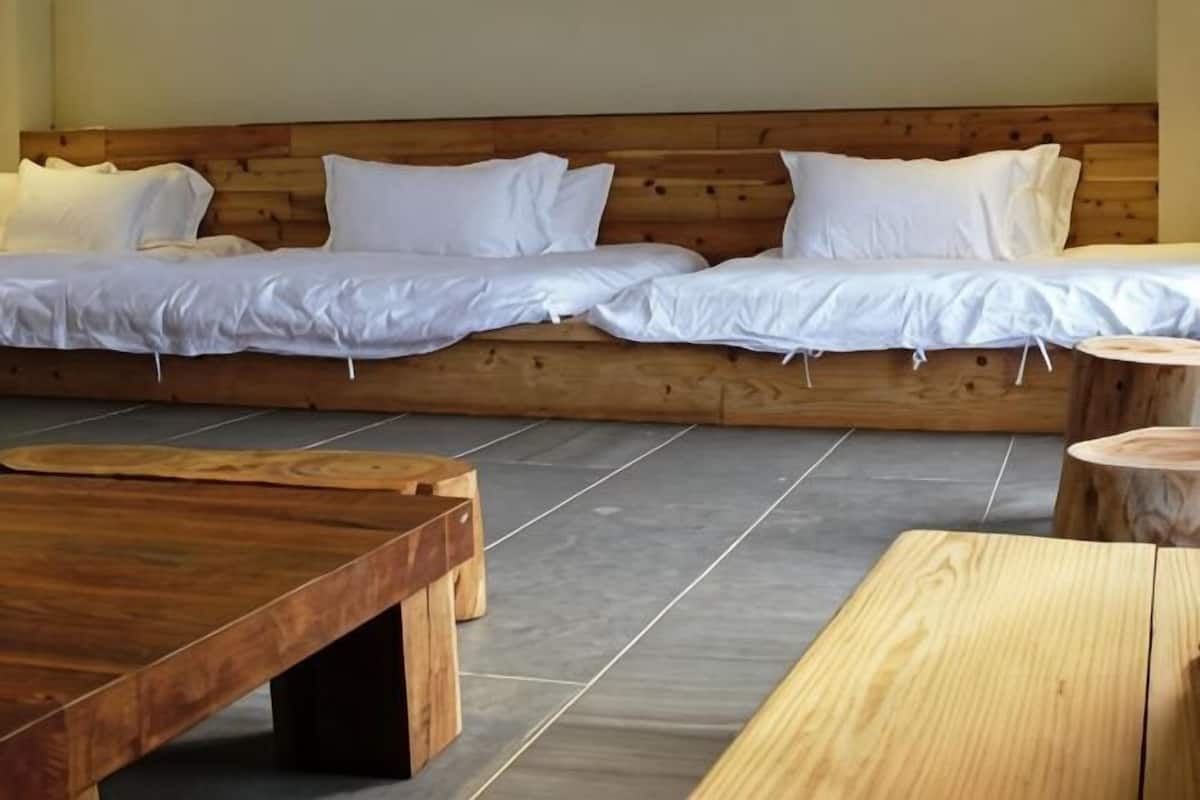 Une chambre avec un lit doté d’une tête de lit en bois, une table basse en bois et une table ronde en bois.
