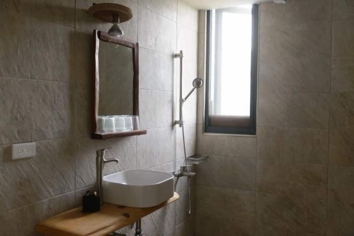 Badkamer | Een douche, een haardroger, pantoffels, handdoeken