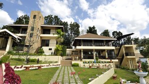A multi-story hotel with a stone tower, multiple balconies, and a well-maintained garden with pathways and statues. - Seascape Resort (Bauan)