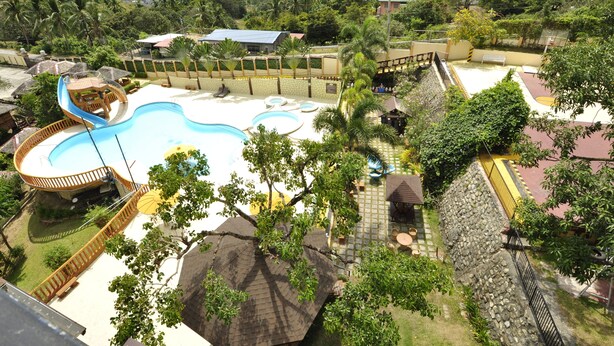 A resort with a large swimming pool, a water slide, and a view of the ocean. - Seascape Resort (Bauan)