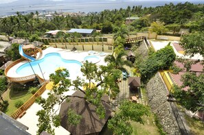 Un resort con una piscina grande, un tobogán de agua y vista al océano.