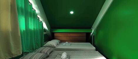 A room with two beds, a wooden headboard, and a green wall.