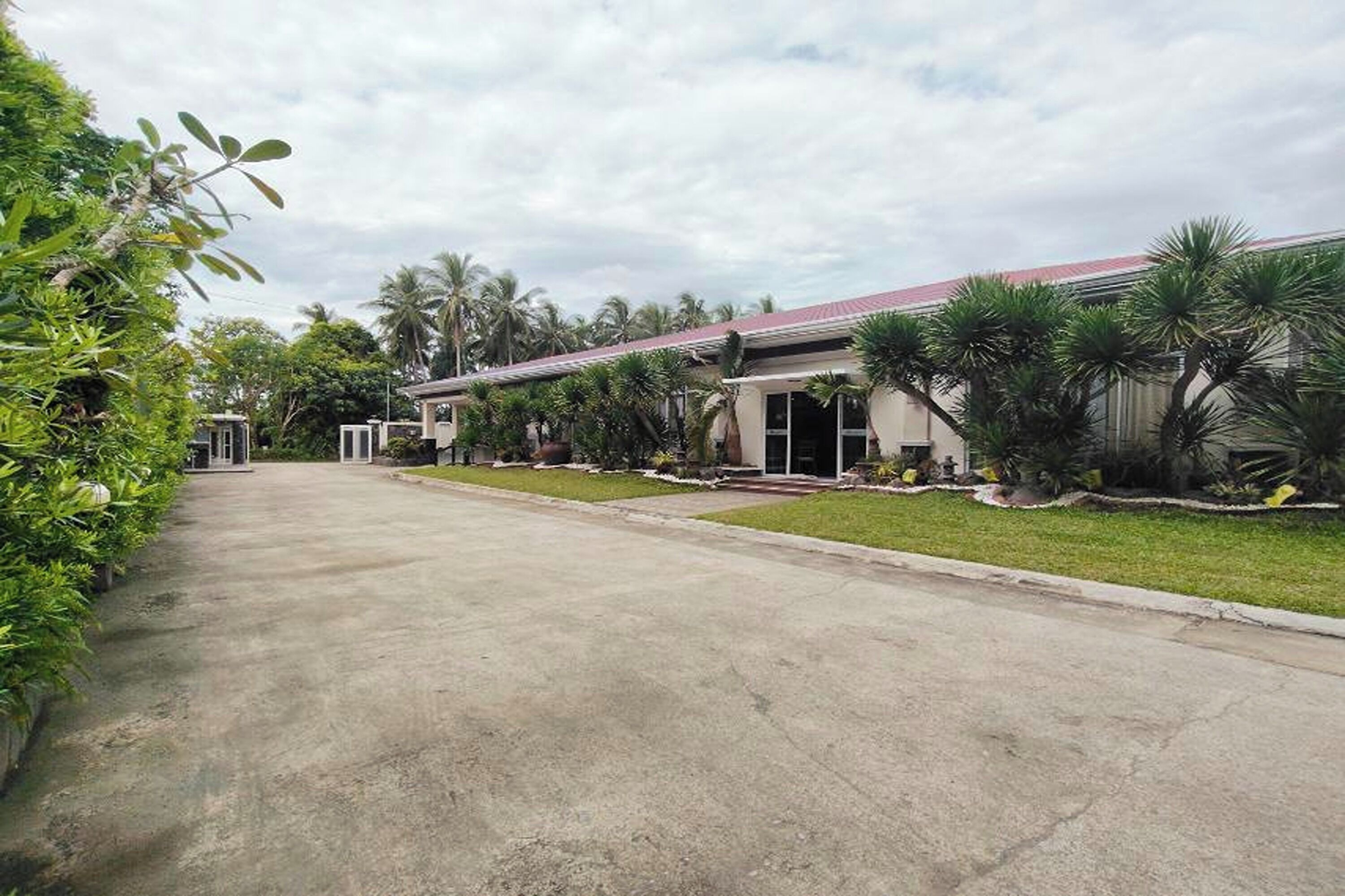 A building with a red roof, surrounded by greenery and palm trees.