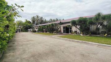 A building with a red roof, surrounded by greenery and palm trees.