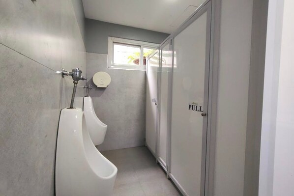 A modern bathroom with two urinals, a toilet, and a window providing natural light. - Angela's Resort and Leisure Farm Laguna (San Pablo)