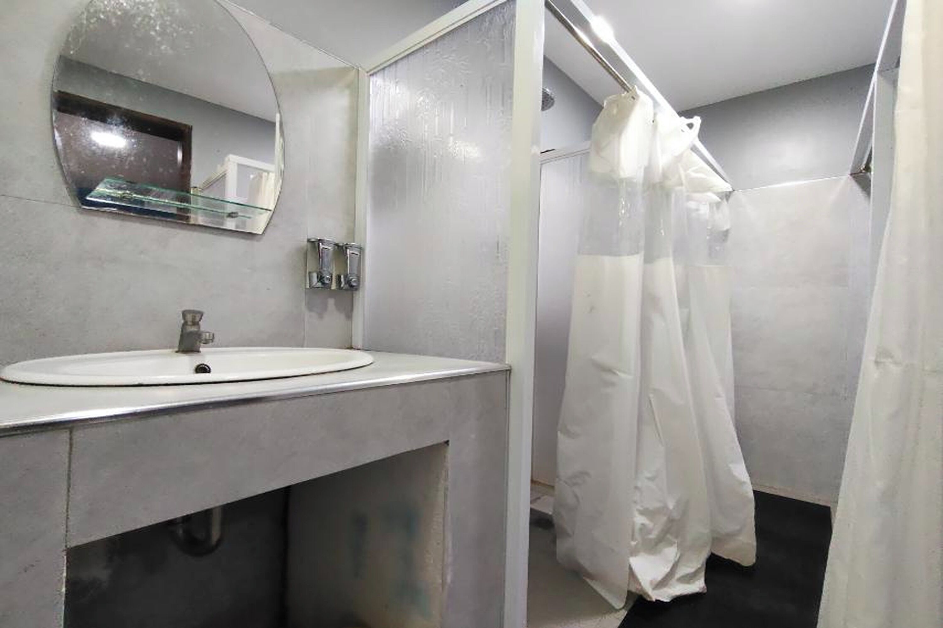 Un bagno con lavandino bianco, uno specchio e una tenda da doccia.