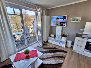 Un salon moderne doté d’un téléviseur, d’un coin repas et d’un balcon.