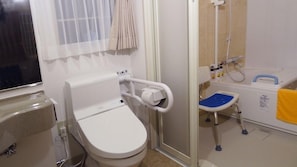Casa de banho pequena e compacta, com sanita, chuveiro e lavatório.