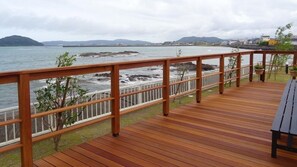 A wooden deck with a railing overlooking a rocky shoreline and calm sea. - Family Lodge Hatagoya Hyuga Kadogawa (Kadogawa)