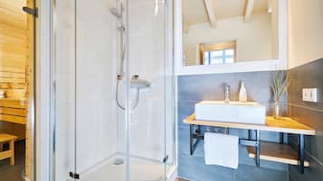 Ein modernes Badezimmer mit einer gläsernen Duschkabine, einer Holzbank, einem weißen Waschbecken und einem großen Spiegel.