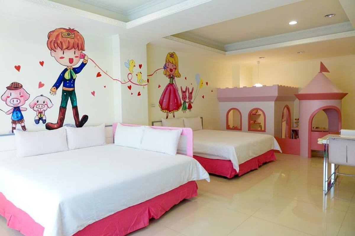 A hotel room with two beds, a play area, and a wall mural.