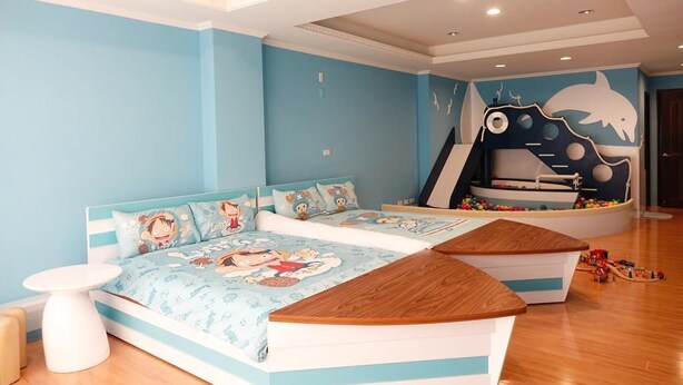 A children's bedroom with a bed, a play area, and a wall mural. - Kid Baby Homestay (Tainan)