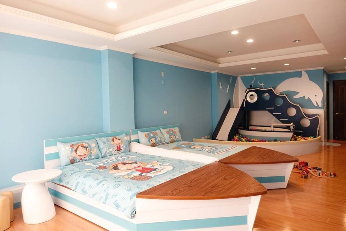A children's bedroom with a bed, a play area, and a wall mural.