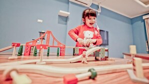 A child playing with a toy bridge in a room with blue walls and an air conditioning unit. - Kid Baby Homestay (Tainan)