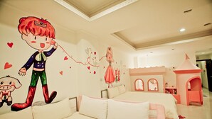 A bedroom with a large bed, a small playhouse, and a wall mural. - Kid Baby Homestay (Tainan)