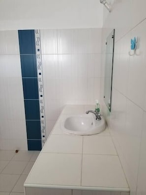 A bathroom with a white sink, a mirror, and a blue accent wall.