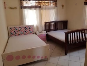 A bedroom with two single beds, a small bedside table, and a nightstand.