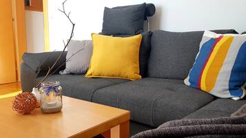 A modern living room with a grey sofa, a wooden coffee table, and a vase with a candle.
