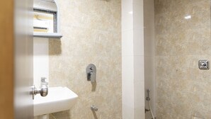A bathroom with a white sink, a shower, and a toilet. - Hotel Elite 59 (Mumbai)