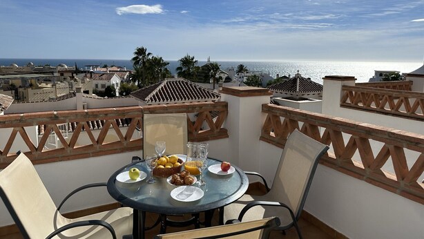 A round table with chairs on a balcony overlooking a coastal view. - Nerja Paradise Rentals - Apartment Chimenea C1D (Nerja)