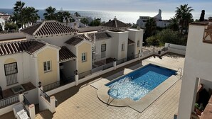 A rooftop pool with a view of the sea, surrounded by buildings with tiled roofs and balconies. - Nerja Paradise Rentals - Apartment Chimenea C1D (Nerja)