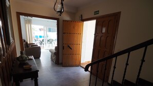 A hallway with a wooden door, a staircase, and a table with a vase and a basket. - Nerja Paradise Rentals - Villa Kaisaras (Nerja)