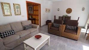 A living room with a beige sofa, a wicker armchair, and a white coffee table. - Nerja Paradise Rentals - Villa Kaisaras (Nerja)