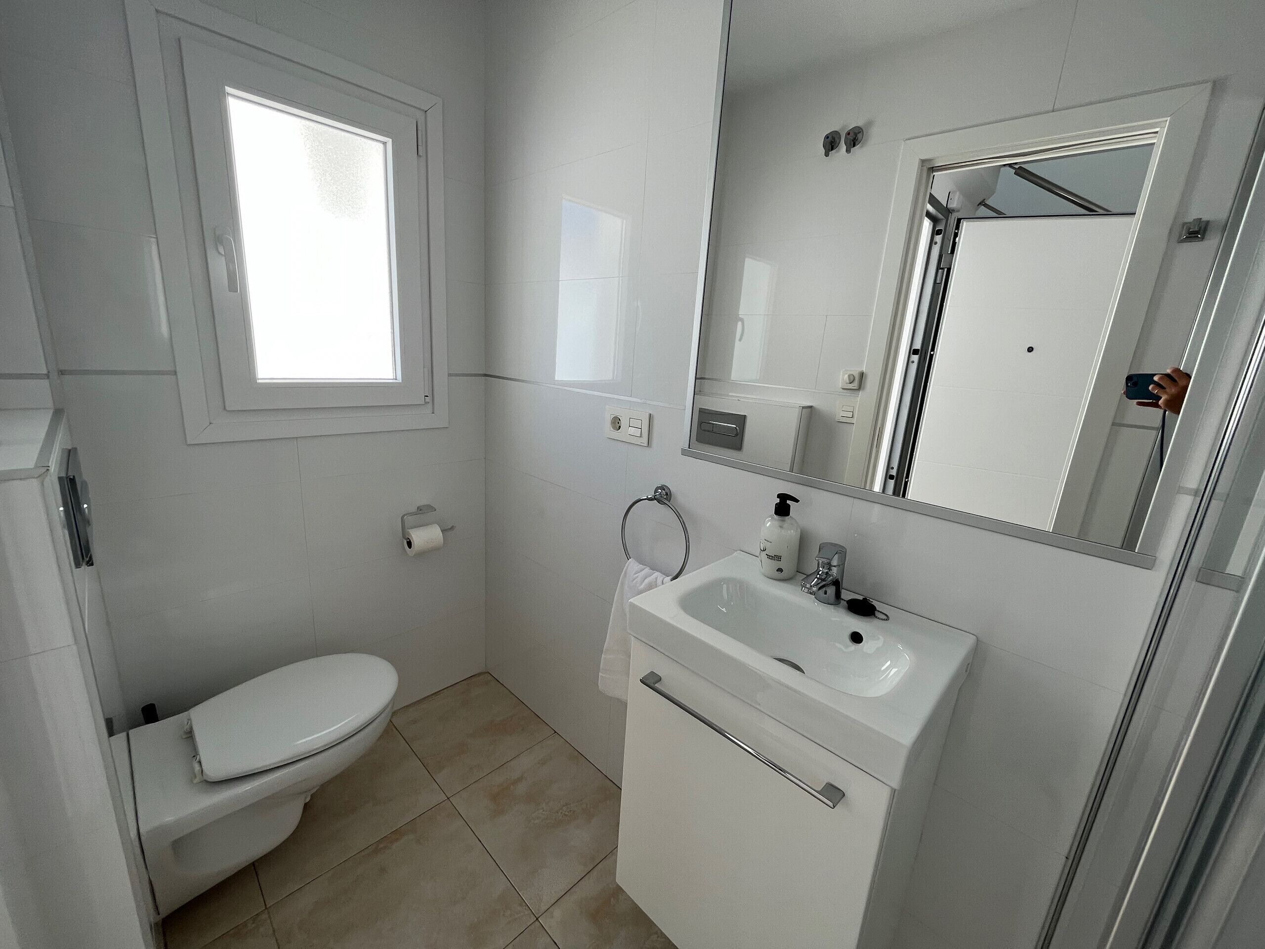 A small, modern bathroom with a toilet, sink, and mirror.