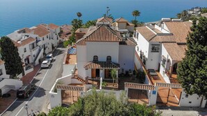 Un quartier résidentiel en bord de mer, caractérisé par des bâtiments blancs, des toits recouverts de tuiles rouges et une vue dégagée sur la mer.