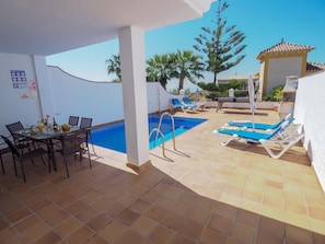 Relax by the pool with a meal at this outdoor dining area, featuring a swimming pool and comfortable lounge seating.