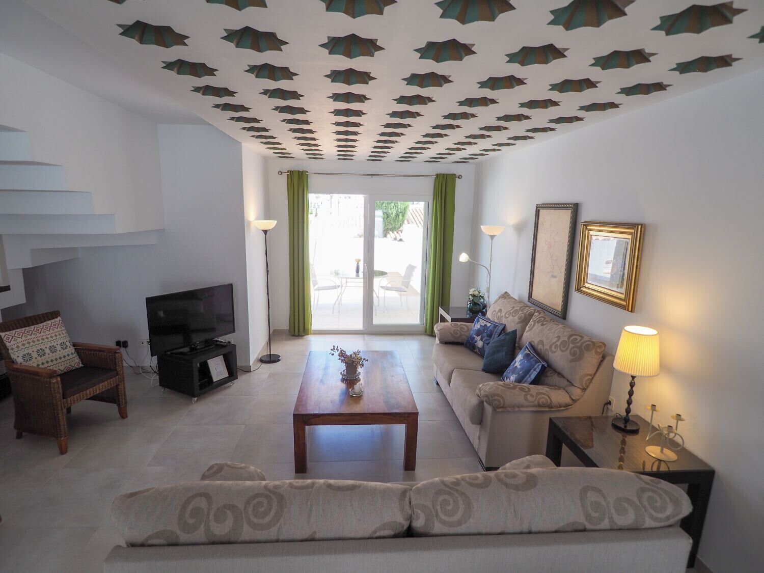 A living room with a sofa, a coffee table, a TV, and a staircase.