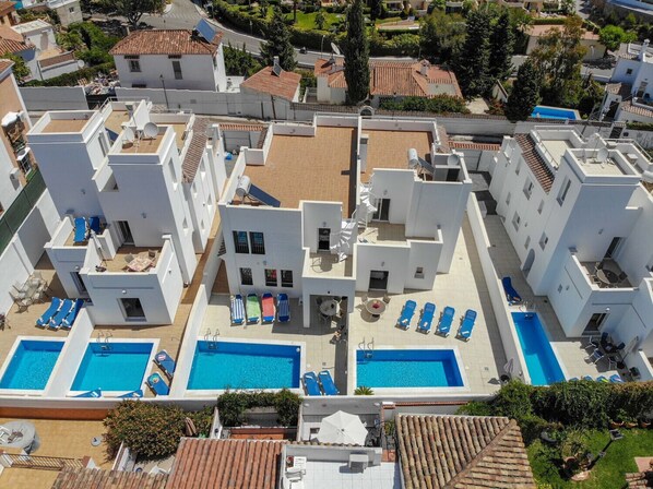 Un hôtel moderne doté de plusieurs piscines, de chaises longues et d’une terrasse sur le toit.